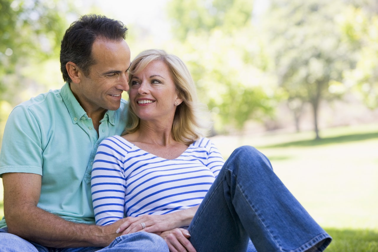 Couple Relaxing Outdoors In Park Smiling