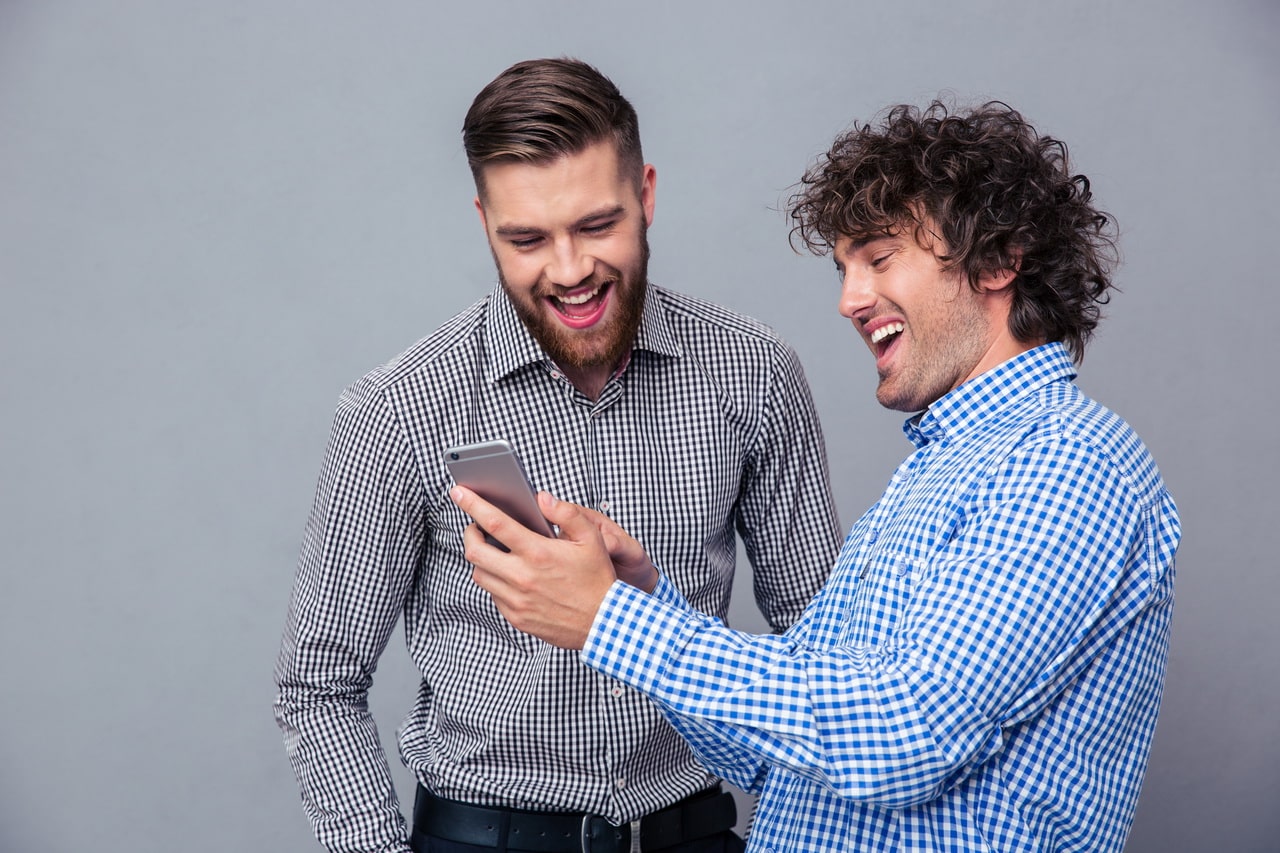 Two Laughing Men Using Smartphone